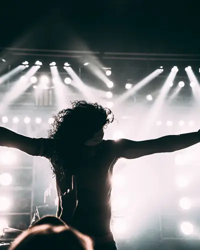 Jax Merritt with arms outstretched in front of stage lights
