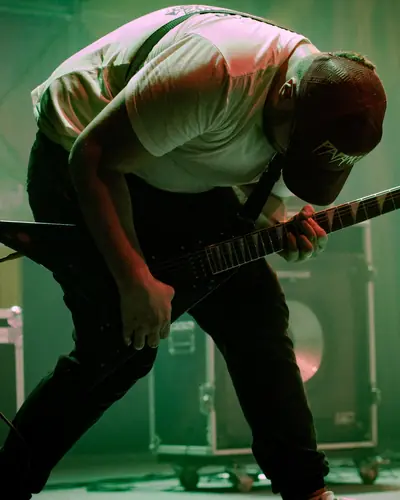 Luis Ferreira bent over his guitar under green stage light