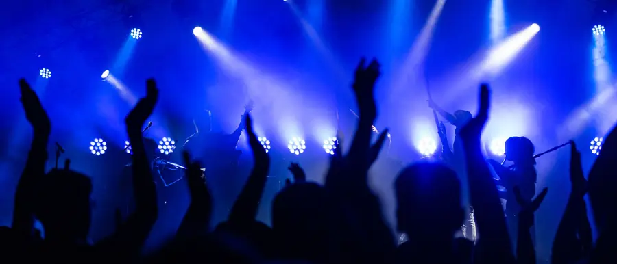 Crowd with raised hands under blue stage lights